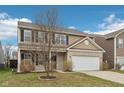 Charming two-story home featuring a brick and siding facade, black shutters, and an attached two-car garage at 6302 Emerald Field Way, Indianapolis, IN 46221
