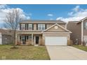 Charming two-story home featuring a brick and siding facade, black shutters, and an attached two-car garage at 6302 Emerald Field Way, Indianapolis, IN 46221