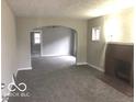 Open-concept living room features neutral paint, new carpet, a fireplace and an arched doorway at 923 N Denny St, Indianapolis, IN 46201