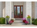 Elegant front door with decorative glass, surrounded by colorful potted flowers and lush greenery at 995 Westlake Hills Dr, Columbus, IN 47201