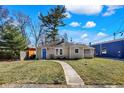 Charming single-story home featuring a bright blue door, neutral siding, and a well-maintained front yard at 1023 Helen Dr, Indianapolis, IN 46240