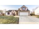 A charming two-story house featuring brick and vinyl siding, an attached garage, and mature landscaping at 10893 Cannonade Ct, Indianapolis, IN 46234