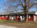 Charming exterior of home with red siding, white trim, a lawn with mature tree and lovely landscaping at 210 Evergreen St, Morgantown, IN 46160