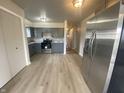 A kitchen view shows stainless steel refrigerator, gray cabinets, stone countertops, and light-colored wood-look flooring at 238 N 7Th Ave, Beech Grove, IN 46107