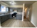 A kitchen featuring gray cabinets, stone countertops, stainless steel appliances, and light wood-look flooring at 238 N 7Th Ave, Beech Grove, IN 46107