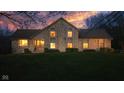 A picturesque stone home at dusk, featuring warm interior lighting and a beautiful sunset backdrop at 241 Melissa Ann Ct, Indianapolis, IN 46234