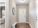 Modern entryway with a white front door, bench seating, sleek mirror, and stylish wood flooring at 4313 W Hidden Preserve Cv, New Palestine, IN 46163