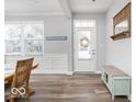 Bright entryway with wood-look floors, decorative wall trim, a bench, coat rack and a charming 'Let's Stay Home' sign at 1040 Arthur Ct, Greenfield, IN 46140