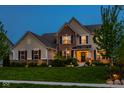 Twilight view of stunning two-story home with brick and siding exterior, well-manicured lawn and trees at 12127 Whisper Ridge Dr, Noblesville, IN 46060