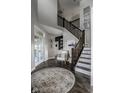 Inviting foyer with dark wood floors, staircase, area rug, and French doors to another room at 12127 Whisper Ridge Dr, Noblesville, IN 46060
