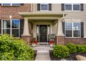 Charming front porch with black door, beautiful wreath, side windows, and manicured landscaping at 12127 Whisper Ridge Dr, Noblesville, IN 46060