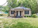 Charming home with dark shutters, covered porch, and a lush green yard, nestled among mature trees at 1707 N Leland Ave, Indianapolis, IN 46218