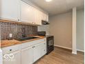 Well-lit kitchen featuring white cabinets, butcher block countertops, and modern black appliances at 1707 N Leland Ave, Indianapolis, IN 46218