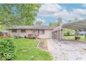 A quaint single-story house with a covered parking area and a green lawn at 613 Barrett St, Danville, IN 46122