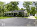 Charming single-story home featuring a stone facade, mature trees, and a spacious asphalt driveway at 6204 S Madison Ave, Indianapolis, IN 46227