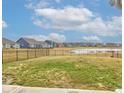 Large backyard with grass and a pond view surrounded by a fence in a quiet community at 6615 Aberdeen Dr, McCordsville, IN 46055