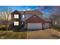 Two-story brick home with attached two-car garage, well-lit and inviting in the evening at 983 Geronimo Dr, Greenfield, IN 46140
