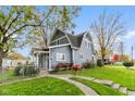 Charming two-story home featuring mature trees, a well-manicured lawn and garden, and a walkway at 117 N Leland St, Fortville, IN 46040