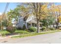 Charming two-story home featuring a welcoming front porch and mature trees in a well-maintained lawn and fall colors at 117 N Leland St, Fortville, IN 46040