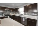 Kitchen boasts modern stainless-steel appliances, dark wood cabinets, and bright white countertops at 13777 N Rising Sun E Cir, Camby, IN 46113