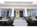Inviting front porch with stylish columns, brick accents, comfortable seating, and a cheerful yellow front door at 1671 Avondale Dr, Westfield, IN 46074