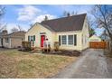 Yellow home with black shutters, a red front door, and a paved driveway at 1711 Kessler E Blvd, Indianapolis, IN 46220