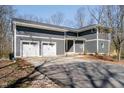 Three car garage with white doors, gray siding and a paved driveway plus mature landscaping at 534 1/2 Amos Dr, Zionsville, IN 46077