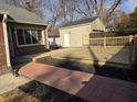 Backyard featuring a new wooden deck, a detached garage, and a brick pathway at 5915 Winthrop Ave, Indianapolis, IN 46220