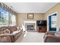 Cozy living room featuring a brick fireplace, large windows, neutral paint, and plush couches at 63 Presidential Way, Brownsburg, IN 46112