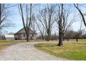 Property showcasing a gravel driveway, mature trees, and a cozy home with a detached garage at 712 N Pendleton Ave, Pendleton, IN 46064