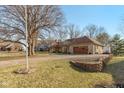View of the home with two-car garage, paved driveway, and mature trees at 8331 Lookout Ct, Indianapolis, IN 46217