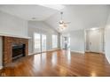 Bright living room featuring a brick fireplace, vaulted ceiling, and wood floors at 9550 Colony Pointe E Dr, Indianapolis, IN 46250