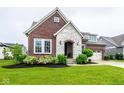 Inviting brick and stone home with a well-maintained lawn and a convenient three-car garage at 12167 Ams Run, Carmel, IN 46032