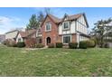 Inviting home exterior with lush green lawn, mature trees, and Tudor-style architecture at 12715 Charing Cross Rd, Carmel, IN 46033