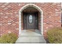 Arched stone entryway features a decorative oval glass front door and brick facade at 12715 Charing Cross Rd, Carmel, IN 46033