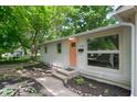 Close up of a ranch-style home's front entrance and landscaped yard, with a vibrant peach-colored door at 1740 Haynes Ave, Indianapolis, IN 46240