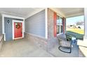 Inviting front porch with stylish seating, brick accents, and a welcoming red door with wreath at 2186 Chick Evans Way, Westfield, IN 46074