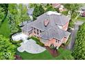 Aerial view of a brick home with a large patio, deck, and meticulously landscaped yard at 8015 Heyward Dr, Indianapolis, IN 46250