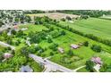 Aerial view displays a charming property with lush green field, barn, and a pond at 905 S Maple St, Fortville, IN 46040