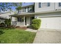 Well-manicured lawn leads up to a house with a charming porch and a convenient three-car garage at 11458 Falling Water Way, Fishers, IN 46037