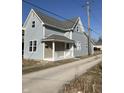 Charming two-story home featuring light blue siding, a covered front porch, and a well-maintained yard at 117 N 10Th St, Elwood, IN 46036