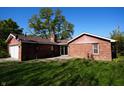 Charming brick home featuring a detached garage, lush green lawn, and a private patio at 1509 E Centennial Ave, Muncie, IN 47303