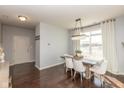 Bright dining room boasts hardwood floors, modern chandelier, and large window with natural light at 18108 Cristin Cir, Westfield, IN 46062