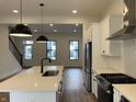 Bright, modern kitchen with white cabinetry, pendant lighting, stainless steel appliances, and hardwood floors at 457 Mariposa Trl, Carmel, IN 46032
