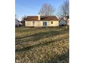 Backyard view of single story home with tan siding and chimney, plus a large grassy lawn at 485 Paddlebrook Dr, Danville, IN 46122