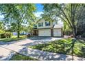 Traditional home with a large driveway, mature trees, well-manicured lawn, and brick-accented two car garage at 6119 Denise Dr, Indianapolis, IN 46221