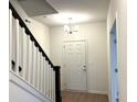 Bright entryway featuring a staircase with black railing, front door, and modern light fixture above at 6724 Seattle Slew Dr, Whitestown, IN 46075