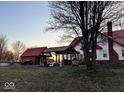 Backyard view of a white farmhouse with a red roof next to a covered outdoor seating and BBQ area at 8089 W Old State Road 67, Paragon, IN 46166