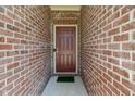 Close-up of the brick entryway with a solid red front door, and a small green welcome mat at 10890 Poppy Hill Dr, Indianapolis, IN 46234