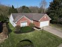 Well-maintained brick home with a two-car garage, manicured lawn, and mature trees at 11598 Wilderness Trl, Fishers, IN 46038